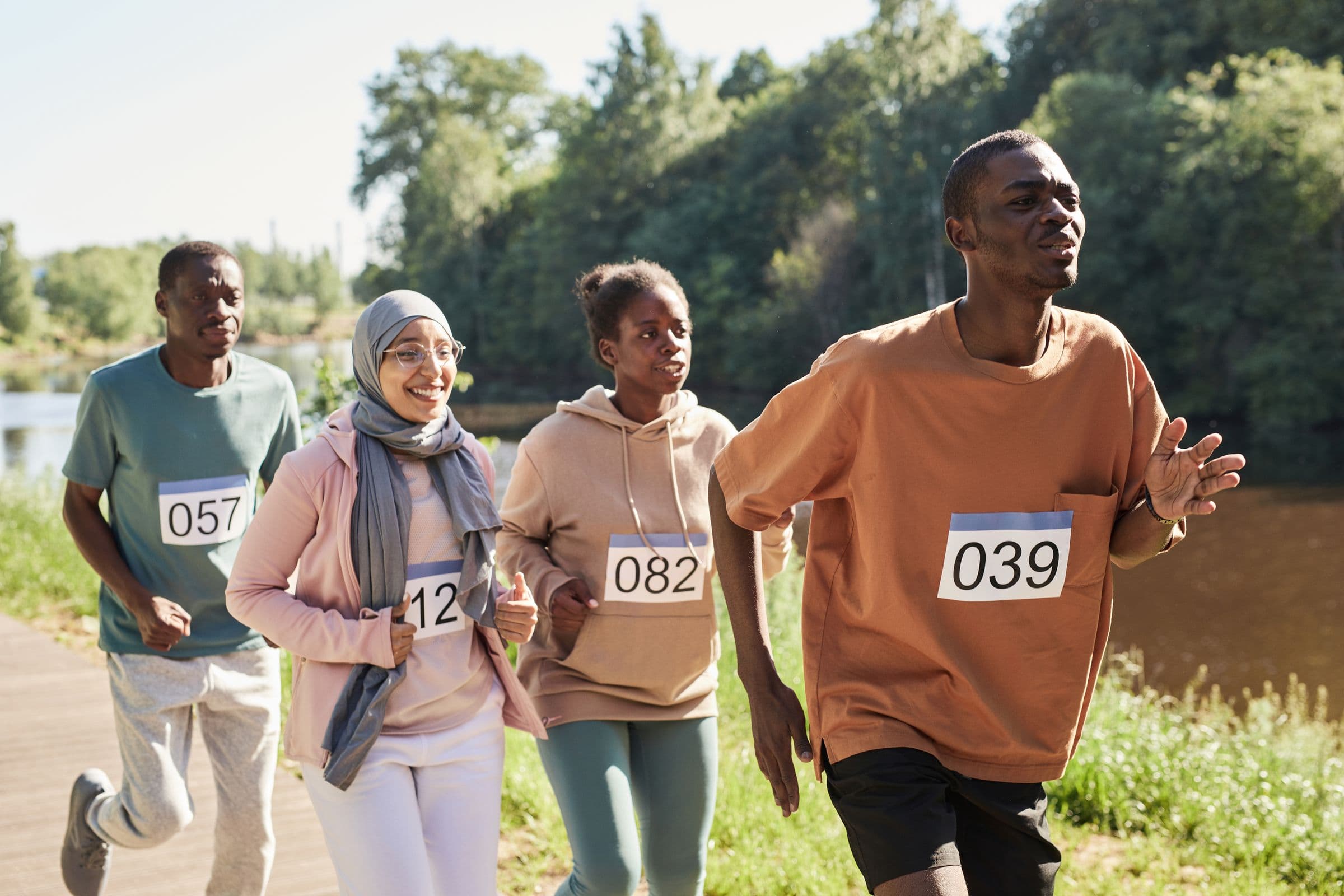 A mixed group of men and women running together on a park path